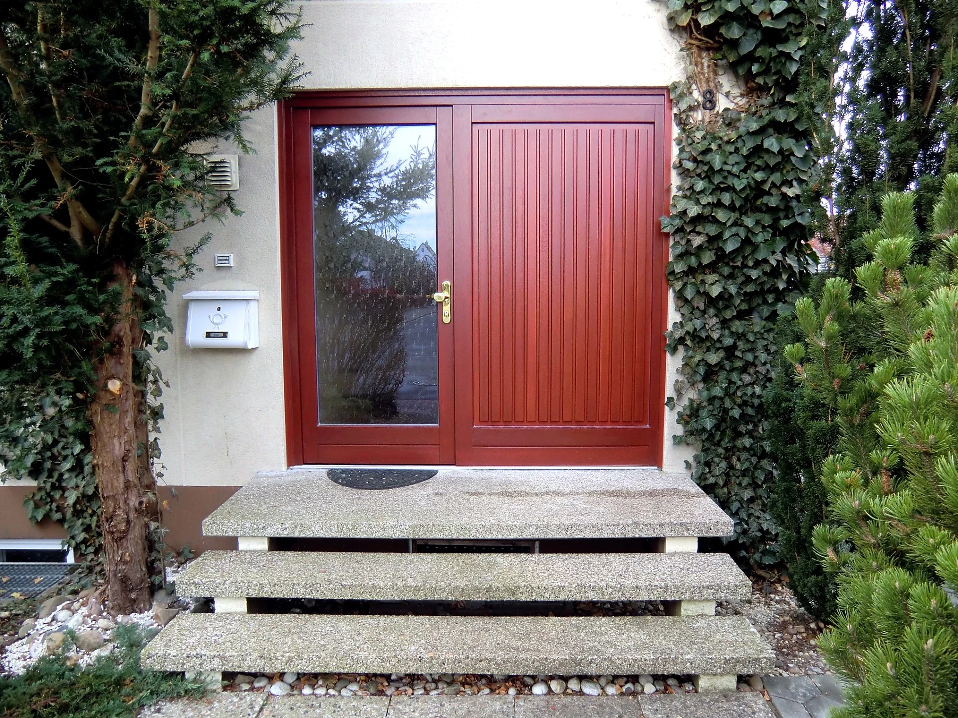 Holzhaustür mit Seitenteil und Glaseinsatz im Eingangsbereich eines Wohnhauses